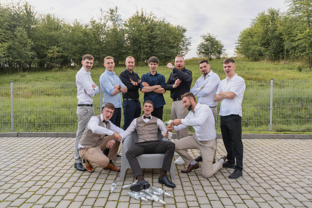 Grupowy portret mężczyzn na zewnątrz podczas wesela.