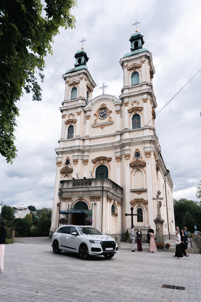 Samochód przed fasadą kościoła w dniu ślubu.