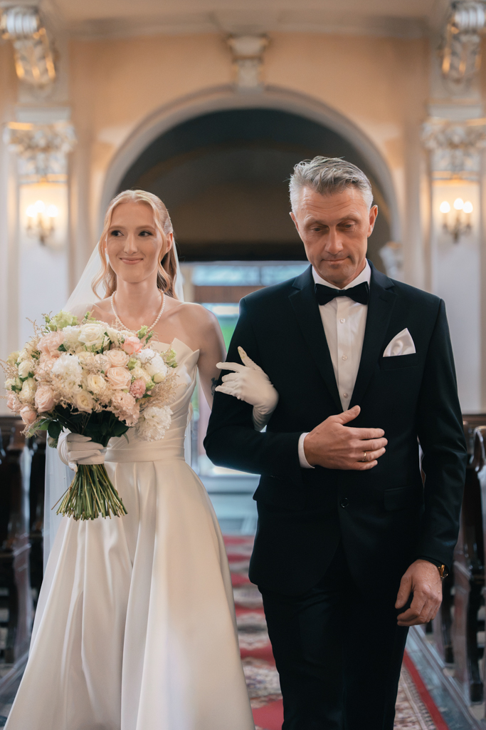 Panna młoda z bukietem pod rękę z mężczyzną w kościele.