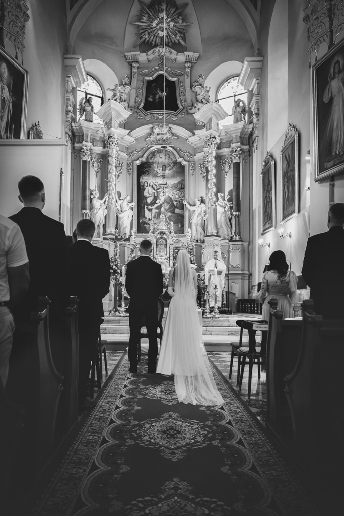 Czarno-białe zdjęcie ceremonii ślubnej z widokiem na ołtarz.