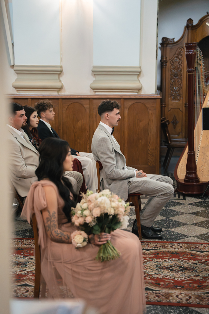 Goście ślubni siedzący w ławkach kościoła.