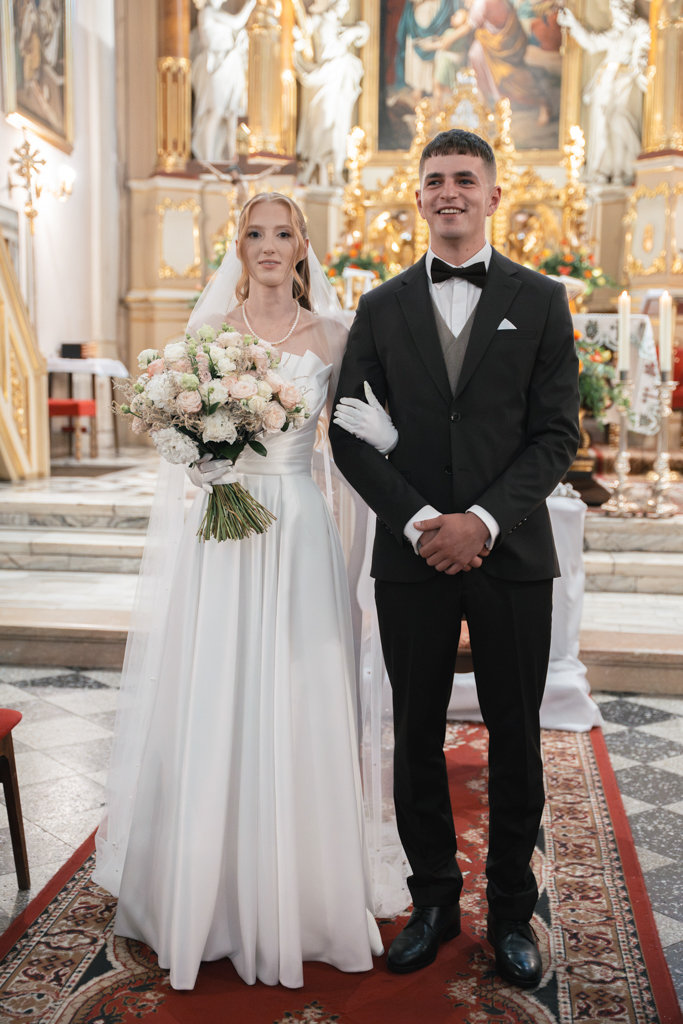 Para młoda pozująca we wnętrzu kościoła po ślubie.